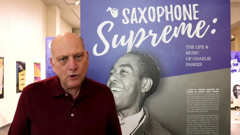 Chuck Haddix explaining a poster: Saxophone Supreme: The life & Music of Charlie Parker